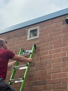 Dylan McCann inspecting an open wall vent before sealing it, Wilkes County, NC