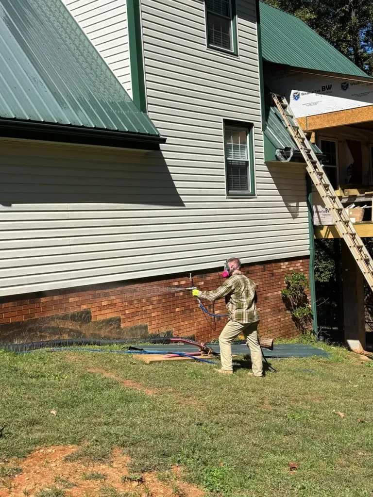 Skeeter's Pest Control technician spraying a perimeter pest treatment along a home's foundation