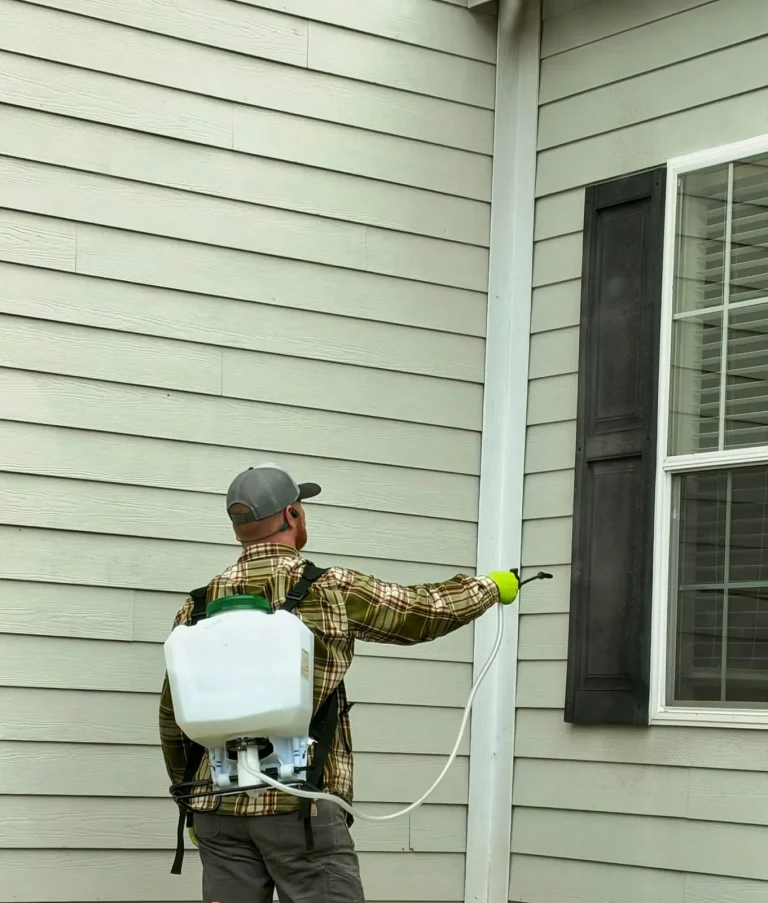 Skeeter's Pest Control technician treating a home's siding with a backpack sprayer